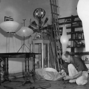 Photographie d’Isamu Noguchi travaillant sur des prototypes d’Akari, vers 1951